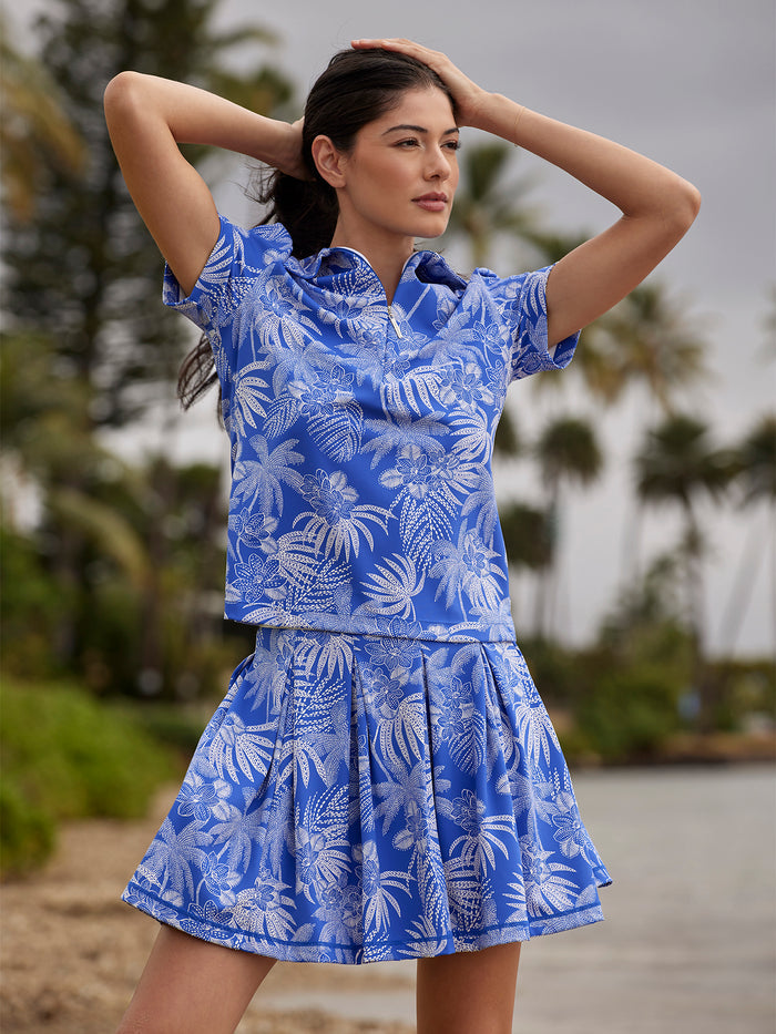 Light blue solid short-sleeve polo shirt,  leaf-print pattern, worn by a model; hands on head.