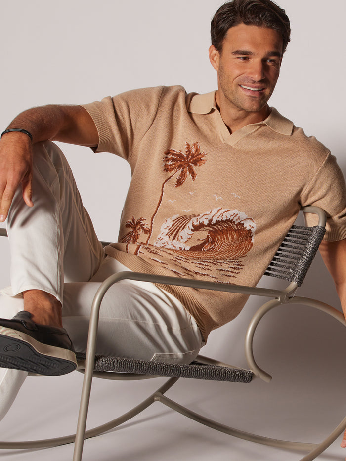 White palm tree and wave-print sweater polo, front seated view.