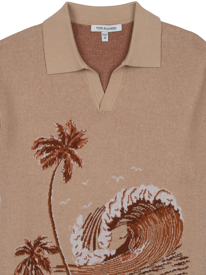 Beige sweater polo with brown and white knit palm trees, ocean waves, and birds, front view.
