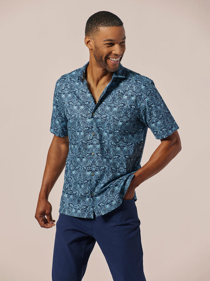 Mixed fished patter-pattern cotton lawn shirt and blue pants, man standing with hand in pocket, front view.