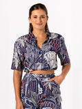 Blue patterned blouse and pants, side view,model smiling, hand in pocket.