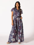 Blue and white patterned short-sleeve jumpsuit, wide legs, hands in pockets, front view.