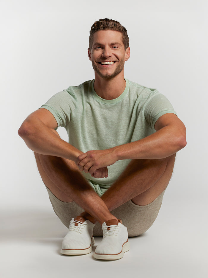 Light green Vacay T-shirt, solid color, man sitting cross-legged on floor, front view