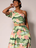 Green floral asymmetrical dress, front view, model smiling and touching hair.