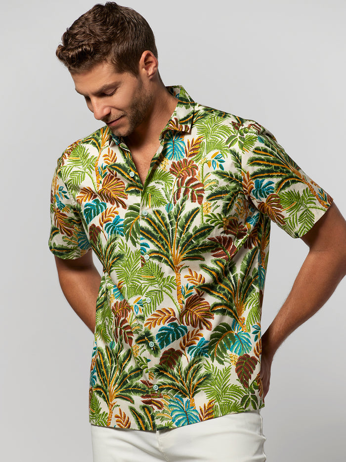 Yellowish tropical-print short-sleeve shirt, back view, model looking down.