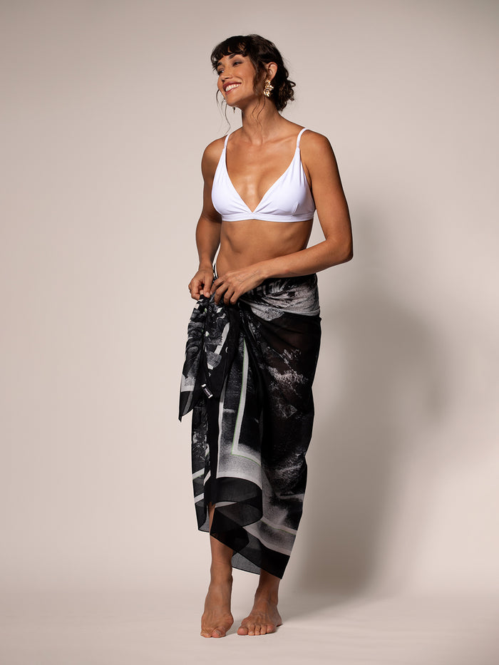 White bikini top with black with white landscape-print pareo, standing front view.