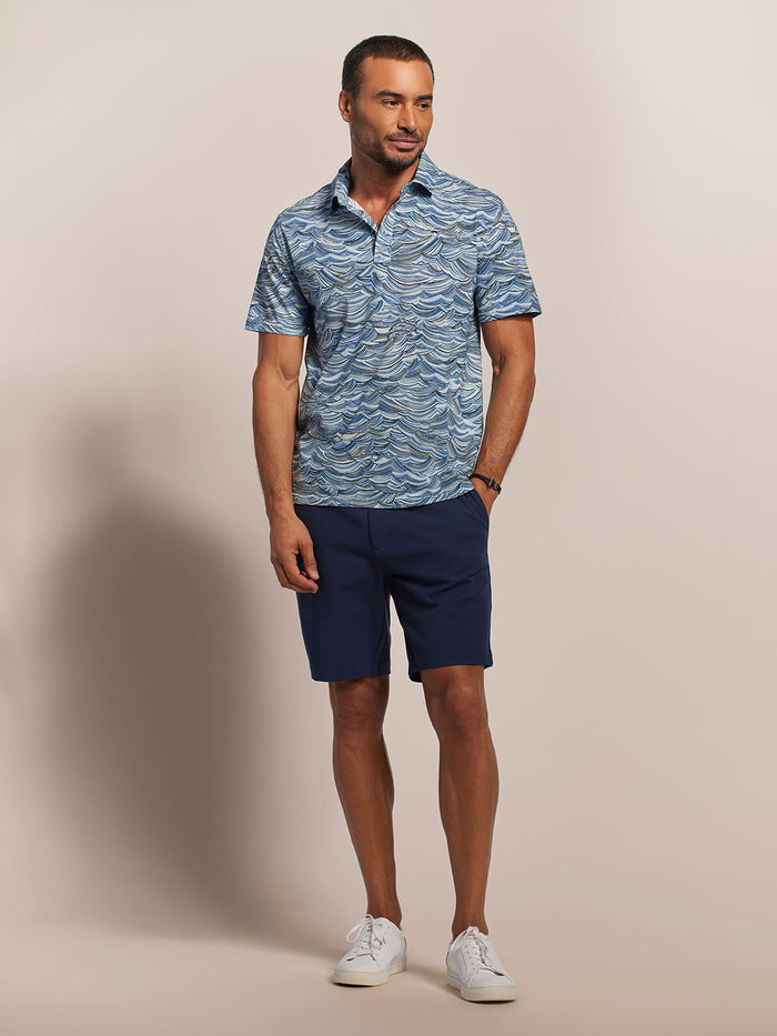 Light blue short-sleeve polo, navy shorts, and white sneakers, full-length front view in both images.