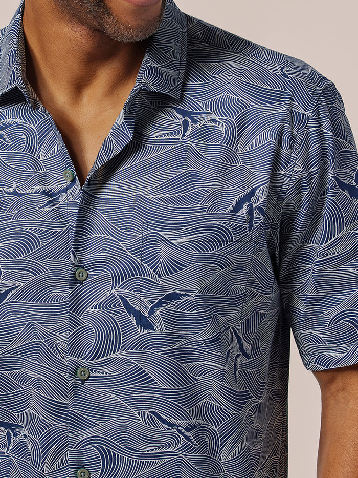 Blue ocean, whale and bird print short-sleeve shirt, partial front torso view.