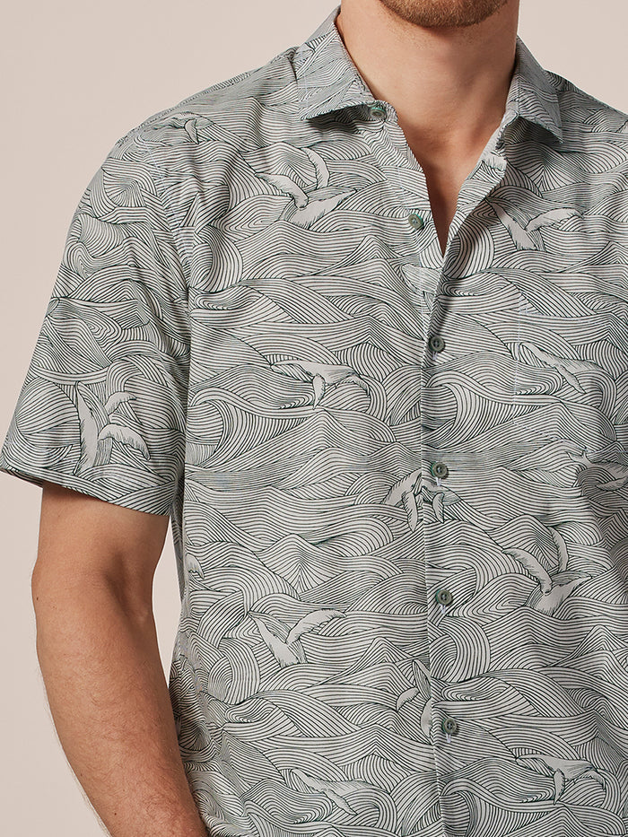 Blue wave and bird print short-sleeve shirt, shoulders to waist view.