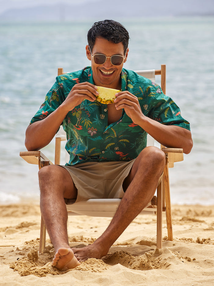 Green graphic-print Zenscape short-sleeve shirt, model in seated view with sunglasses and pineapple slice